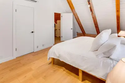 a bedroom with a white bed and a wooden floor at Community Pool Modern Cabin in Pine Mountain Club in Pine Mountain Club