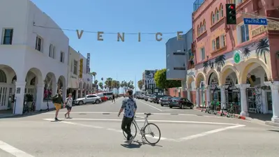 a man crossing a street with a bike in the street at Studio, 5 minutes to Venice Beach Free Parking! in Los Angeles