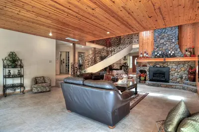 a living room with a leather couch and a stone fireplace at No. 8 Estate By The Lake in Big Bear Lake