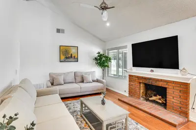 a living room with a fireplace and a flat screen tv at Huntington Beach Home Fire Pit, Grill and More! in Huntington Beach