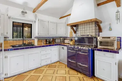 a kitchen with white cabinets and purple appliances at Hollywood Hills Walk to Universal City Views in Los Angeles