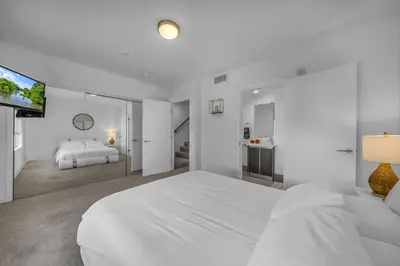 a white bedroom with a large bed and a flat screen tv at Amazing, Spacious Unit, Heart LA in Los Angeles