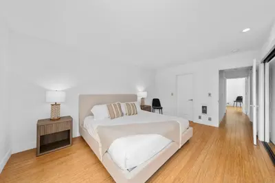 a white bedroom with a white bed and a wooden floor at The Orchid-Beachfront Bliss Spacious 2BR Apt In Santa Monica in Los Angeles