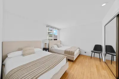 a bedroom with two beds and a chair and a window at The Orchid-Beachfront Bliss Spacious 2BR Apt In Santa Monica in Los Angeles