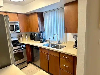 a kitchen with wooden cabinets and a sink at Mid-City Charm 2BR Near LAs Hotspots! in Los Angeles