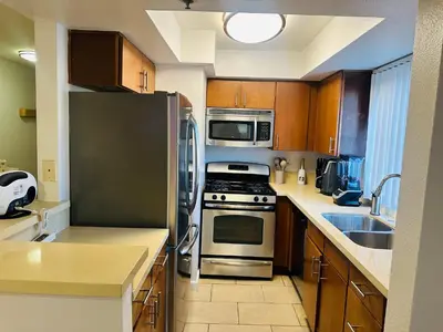 a kitchen with stainless steel appliances and wooden cabinets at Mid-City Charm 2BR Near LAs Hotspots! in Los Angeles