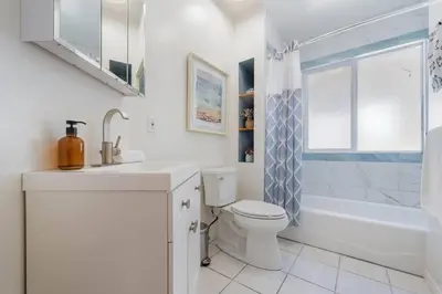 a white bathroom with a toilet and a sink at Woodland Victory Hideaway in Tarzana