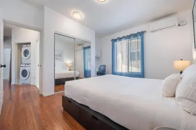 a bedroom with a large white bed and a room with a bed sqor at Woodland Victory Hideaway in Tarzana