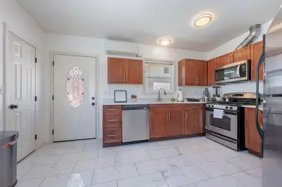 a kitchen with wooden cabinets and a white tile floor at Woodland Victory Hideaway in Tarzana