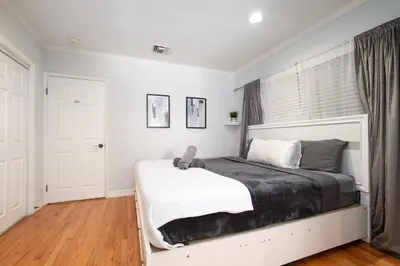 a bedroom with a large bed with white walls and wood floors at Elegance Escape Sleeps 10 Pool with Jacuzzi in Los Angeles