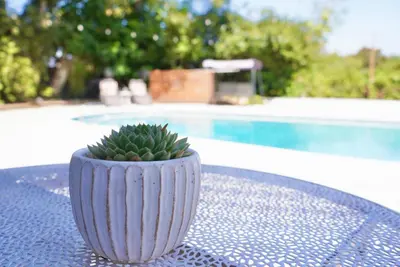 a white vase sitting on a table next to a pool at Sunny Days Tiny House with private entrance, pool and view in West Covina