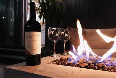 a bottle of wine sitting on a table with wine glasses at Sunny Days Tiny House with private entrance, pool and view in West Covina