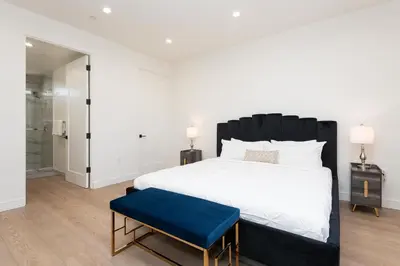 a bedroom with a large bed and a blue stool at Stylish Apartments in Glendale with Free Parking in Glendale