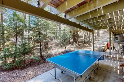 a ping pong table in the middle of a screened in porch at Quiet Wooded Retreat in Lake Arrowhead