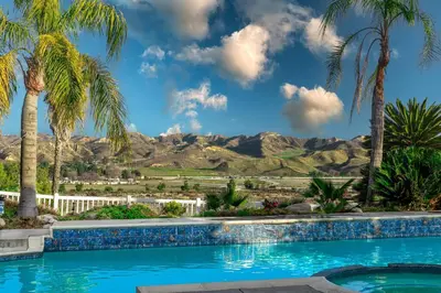 a pool with palm trees and mountains in the background at The Best View in The City! in Castaic