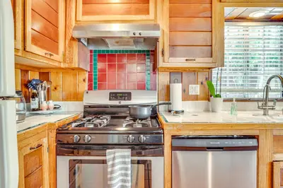 a kitchen with a stainless steel stove and wooden cabinets at Less Than 1 Mi to Venice Beach and Boardwalk! Quiet Cottage in Los Angeles