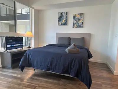 a bedroom with a bed with a blue comforter and a television at Awesome Loft at Hollywood FREE Parking in Los Angeles