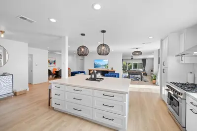 a kitchen with white cabinets and a living room at NEW Lux 5BR Villa Near Disney, Knotts, LA, OC with Hot Tub & Games in Fullerton