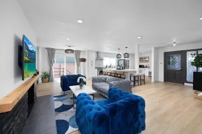 a living room with blue couches and a kitchen at NEW Lux 5BR Villa Near Disney, Knotts, LA, OC with Hot Tub & Games in Fullerton