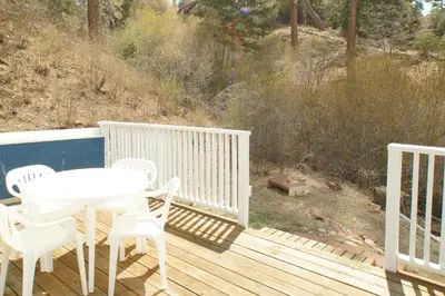 a white table and chairs on a wooden deck at Cozy Bear Cottage - Walk to Lake & Village! in Big Bear Lake
