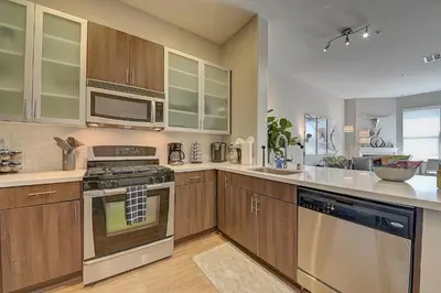 a kitchen with wooden cabinets and stainless steel appliances at Penthouse One Bedroom Garden View Condo by UCLA in Los Angeles