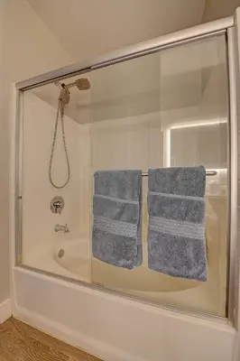 a bathroom with a shower with blue towels on a tub at Penthouse One Bedroom Garden View Condo by UCLA in Los Angeles