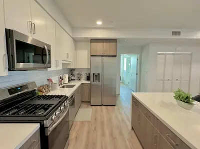 a large kitchen with stainless steel appliances and wooden floors at Corner 2 Bedroom 2 Bath Condo - Balcony - Parking in Los Angeles