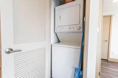 a laundry room with a washer and dryer next to a door at Trendy 2BD 2BTH Apt steps from Downtown Santa Monica! in Los Angeles