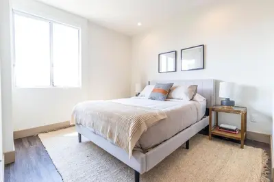 a white bedroom with a bed and a window at Trendy 2BD 2BTH Apt steps from Downtown Santa Monica! in Los Angeles