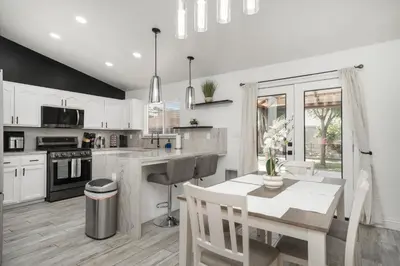 a kitchen with white cabinets and a table with a dining room at Simple Home for Work or Travel in Bakersfield