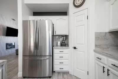 a kitchen with a stainless steel refrigerator and white cabinets at Simple Home for Work or Travel in Bakersfield