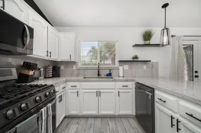 a white kitchen with a sink and a stove at Simple Home for Work or Travel in Bakersfield