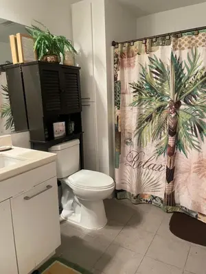 a bathroom with a toilet and a palm tree shower curtain at Tucked in Little Tokyo in Los Angeles