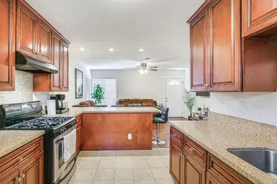 a kitchen with wooden cabinets and a stove top oven at 5 Mi to Coast Centrally Located Long Beach Home! in Long Beach