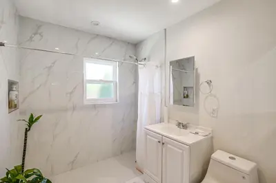 a white bathroom with a toilet and a sink at 5 Mi to Coast Centrally Located Long Beach Home! in Long Beach