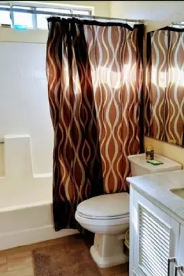 a bathroom with a toilet and a shower curtain at Be our Guest Hm Tampa in Palmdale