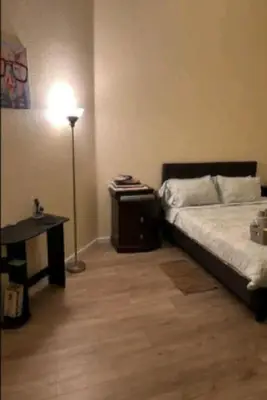 a bedroom with a bed and a desk and a lamp at Be our Guest Hm Tampa in Palmdale