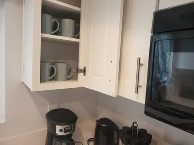 a kitchen with white cabinets with cups and a microwave at High Desert Dream on the Fairway WiFi Smart TVs in Victorville