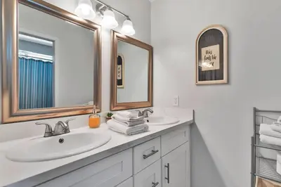 a white bathroom with two sinks and two mirrors at High Desert Dream on the Fairway WiFi Smart TVs in Victorville
