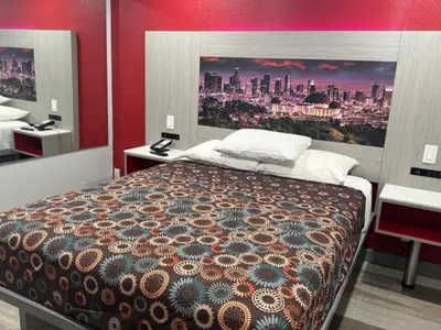 a bedroom with a bed with a painting on the wall at Playa Inn Motel - Long Beach, LA in Long Beach