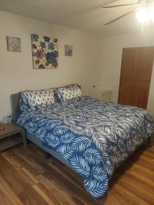 a bedroom with a bed with a blue and white comforter at Lyons lovely house in Hesperia