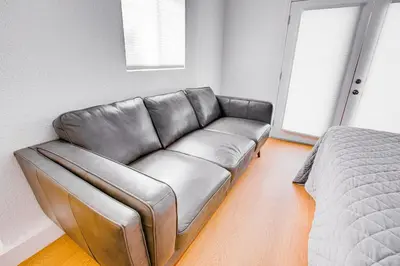 a leather couch in a room with a bed at Cozy Private Studio in Granada Hills Near CSUN, Universal in Mission Hills