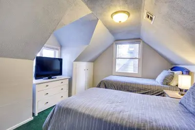 a attic bedroom with two beds and a tv at The Twin Pines Chalet, 2 min to Village, BBQ in Big Bear Lake