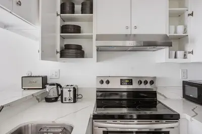 a white kitchen with a stove and a sink at Blueground Mid-Wilshire pool ac nr retail LAX-1265 in Los Angeles