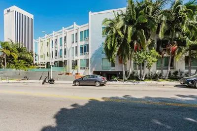 a car parked in front of a building with palm trees at Blueground Mid-Wilshire pool ac nr retail LAX-1265 in Los Angeles