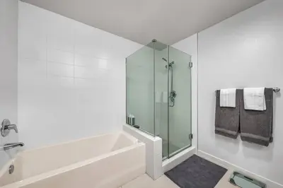 a white bathroom with a tub and a glass shower at Modern & chic in Heart of Downtown Santa Monica in Los Angeles