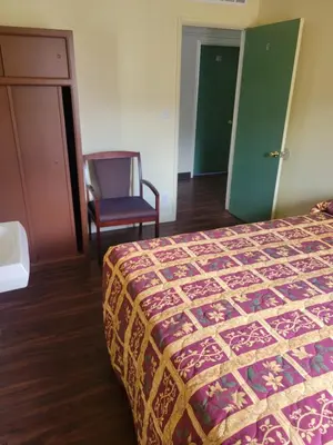 a hotel room with a bed and a chair at Randolph Hotel in Huntington Park