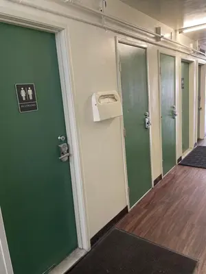 a row of green doors in a hallway at Randolph Hotel in Huntington Park