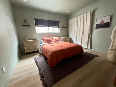 a bedroom with a bed with an orange blanket and a window at 2 Bedroom Tulum Oasis in Hollywood in Los Angeles