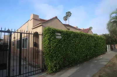 a fence in front of a house with a hedge at 2BR Lit and Spacious in the Heart of Hollywood in Los Angeles